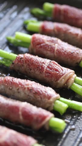 Beef and asparagus rolls pan-fried with oil on a grill pan.
