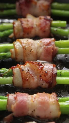 Bacon and asparagus rolls pan-fried with oil on a hot pan. Close-up view