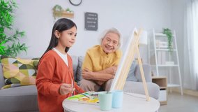 Asian loving grandmother support granddaughter with drawing at home. Caring elderly senior grandma encourage little girl's creativity, enjoying fun and educational art activity together in living room - Powered by Shutterstock - Get 15% off with code: PIKWIZARD15