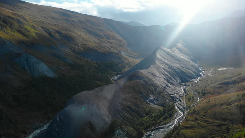 Sunlight piercing through mountain valley with river. Media