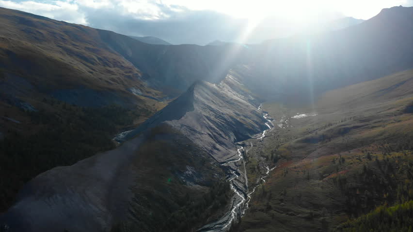 Sunlight illuminating mountain valley with river. Media