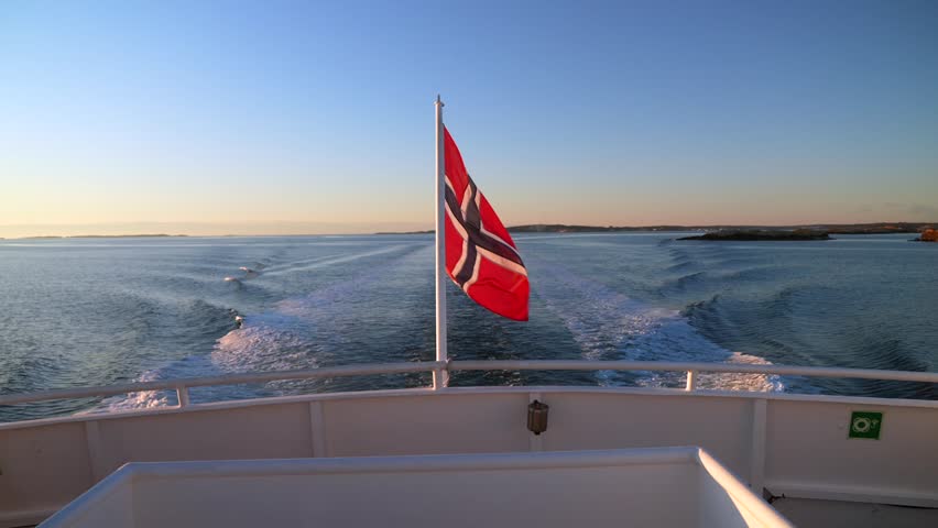 Norwegian Flag wind on ferry Boat ride wake Strömstad Stromstad Oslo Fjord Sweden Sverige Norway Norge golden hour Arctic sunlight sunset Scandinavia islands horizon Natural preserve area coastline