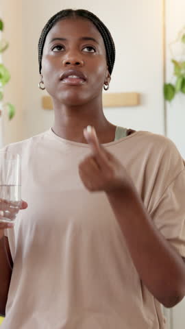 Black woman, drinking and water with medication in home for healthcare, symptoms or side effects. Female person, antibiotic and hydration with glass or pill for medical cure, vitamins or wellness