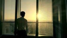 Businessman standing by office window looking outside. - Powered by Shutterstock - Get 15% off with code: PIKWIZARD15