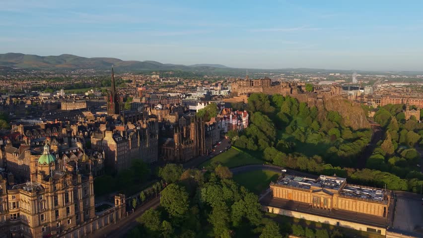 Aerial footage of Edinburgh at sunrise as the city wakes under soft golden light, revealing rooftops, landmarks, and peaceful streets