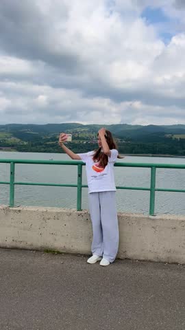 Smiling teenage girl taking a selfie on the cycling path by Czorsztyn Lake, Poland. Concept: teen lifestyle, travel, summer activity, digital generation
