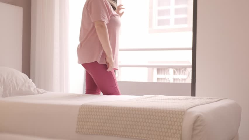 Full-figured woman 50 making bed, dancing lightly near mattress, home chore, joyful routine, domestic life, morning activity, gently dancing to unseen music, Joyful housework moment