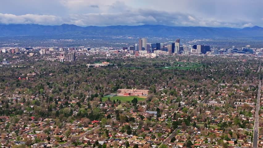 Front Range Denver Lowry Northfield Central Park Colorado aerial drone neighborhood apartment buildings sunny cloudy sky cloudy North High School cars cityscape skyscrapers forward pan up motion