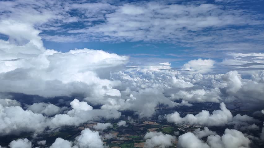 An immersive pilot’s view from an airplane cockpit while flying peacefully through a blue sky full of cottony storm clouds. Ultra-realistic 4K shot.