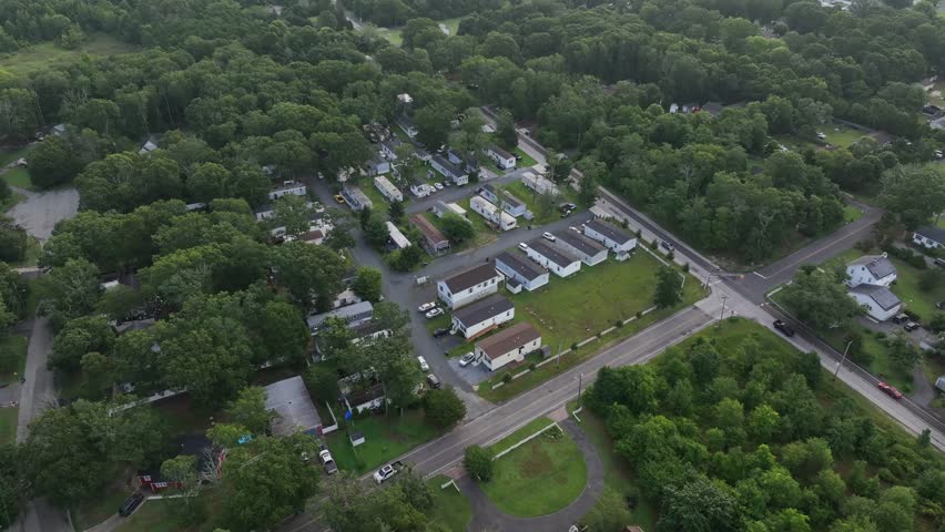 Mobile trailer homes in green suburb district of town. Aerial tilt up shot. Green nature in stone harbor, New Jersey. Wetland and ocean in distance. Sunrise in the morning.