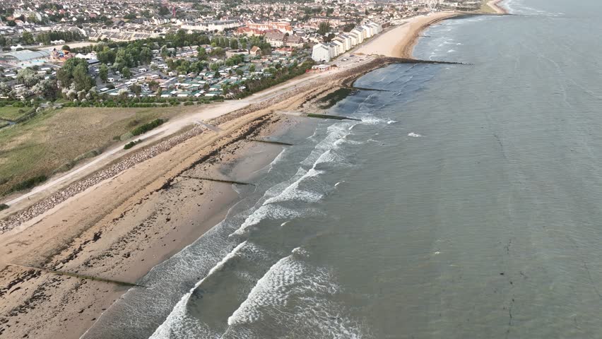 Aerial view of the sandy beach meeting the ocean, with small waves crashing against the shore, Bernières-sur-Mer, Normandy, France.
