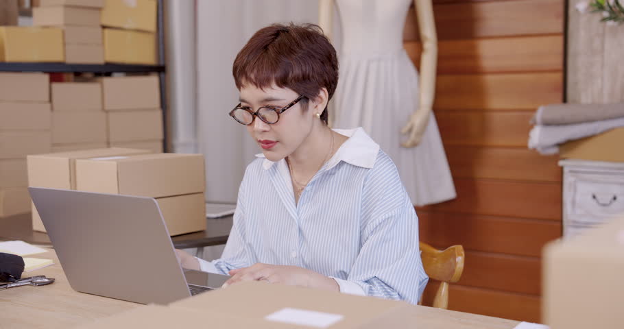 Senior asian mother showing plaid garment smiling while daughter cheering success boutique fashion studio teamwork e-commerce family business online shop handmade textile clothing branding