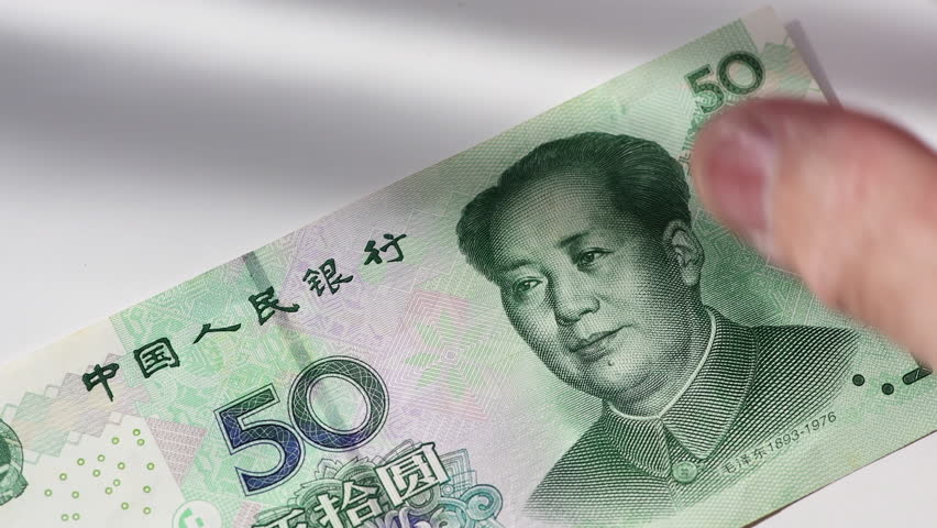 A close up clip of a person counting Chinese Yuan bank notes on a white background.