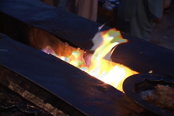 PESHAWAR, PAKISTAN - NOVEMBER 01, 2001: Plates of cooked meat are placed over open flame.