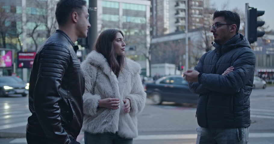 Three friends chat and catch up on a busy city street. They laugh and discuss life events.
