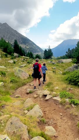 Family hiking together on mountain trail, experiencing scenic wilderness with children and parents enjoying breathtaking landscape under sunny summer sky