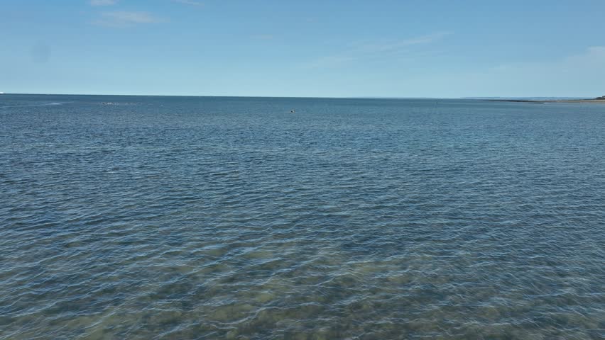 Aerial view of the vast expanse of water meeting the horizon under a clear sky, creating a sense of tranquility, Bernières-sur-Mer, Normandy, France.