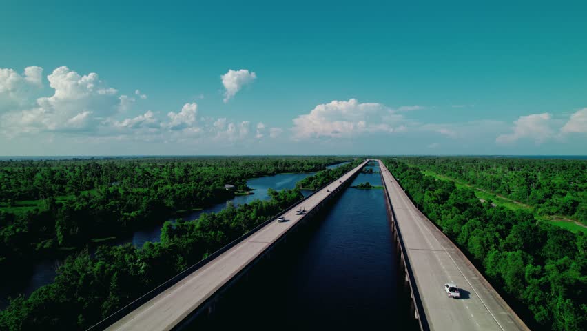 Aerial drone view of twin highway bridges in Louisiana spanning over river and wetlands, symbolizing transport, travel, and infrastructure.