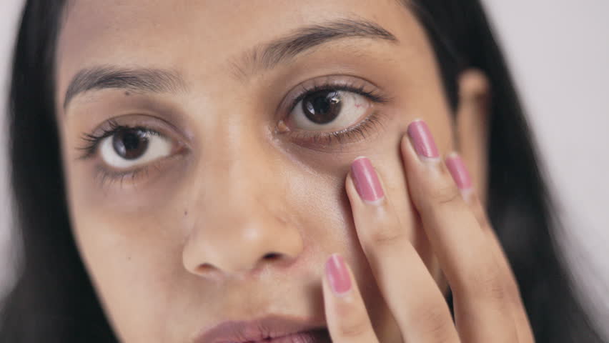 woman showing her under eye dark circle in white background.