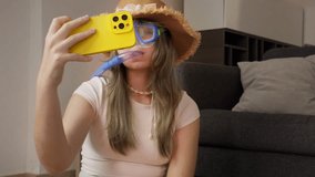 Summer fun concept: teenager girl wearing snorkel gear and straw hat takes selfies with smartphone indoors, humorously preparing for virtual vacation - Powered by Shutterstock - Get 15% off with code: PIKWIZARD15