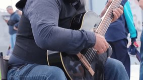 Close-up of mans hands playing acoustic guitar outdoors, performing in public space to earn income through live street music. Moscow, Russia - 08.24.2025 - Powered by Shutterstock - Get 15% off with code: PIKWIZARD15