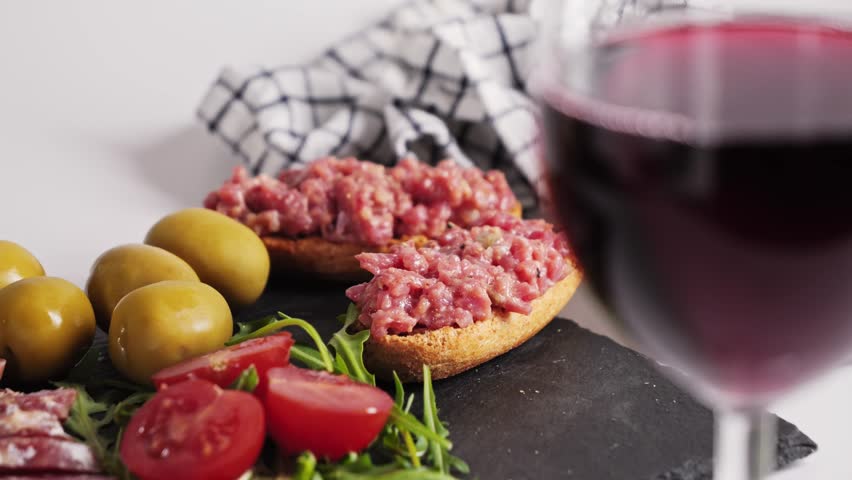 A glass of red wine stands on a table in a restaurant against the background of meat