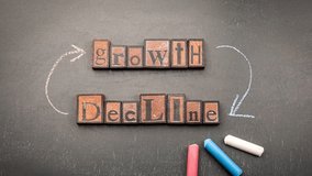 Chalk animation illustrating the economic concept of growth versus decline with directional arrows and wooden block letters on blackboard - Powered by Shutterstock - Get 15% off with code: PIKWIZARD15