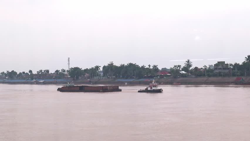 Jambi, Indonesia - August 15, 2025 - Two ships pulling and pushing a boat consisting of coal in the Batanghari River while passing under the Gentala Arasy bridge