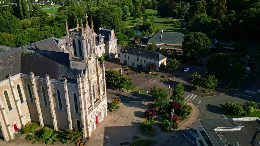 Drone shot descending towards Saint-Pierre Church in Changé, with the Parc des Ondines visible in the background.