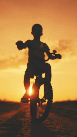 Preschooler resting in country in summer vacation, little boy riding bike, silhouette against sky in sunset. Happy childhood moments, children game in nature, leisure and entertainment, sport activity