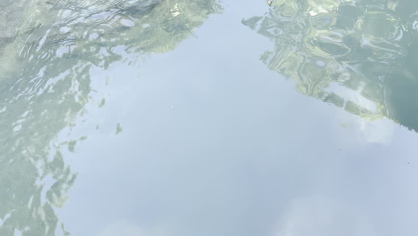 Urban city park with perfect landscape design featuring stone waterfall flowing into pond and stream, gazebos, reflecting palm trees. Golden hour evening sunset light, tranquil relaxing nature scenery