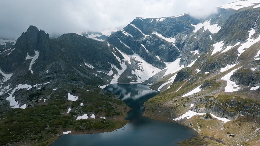 Picturesque summer mountain scene from Seven Rila Lakes in Bulgaria, showing aerial mountain lake surrounded by snowy ridges, ideal for stock focused on hiking, aerial travel, alpine drone, Balkan 
