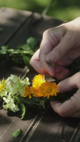 Vertical video. DIY seasonal summer home decor. Hands making floral wreath outdoors