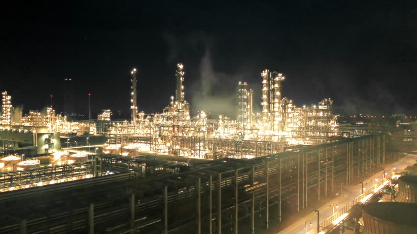 petroleum oil refinery in industrial estate at night, drone aerial view. Fuel and power generation, petrochemical factory industry, or environmental air pollution concept