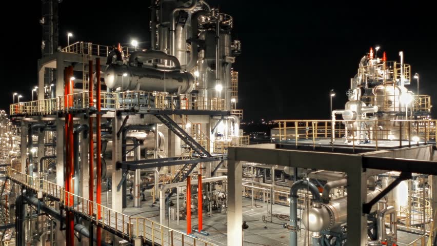 petroleum oil refinery in industrial estate at night, drone aerial view. Fuel and power generation, petrochemical factory industry, or environmental air pollution concept