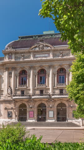 Timelapse hyperlapse of Theatre des Celestins in Lyon, France. A historic theatre on Place des Celestins with trees, benches and people relaxing under blue sky. Classic architecture and cultural charm