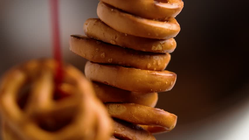Salted pretzels crackers in bunch hanging on red string on brown background. Macro