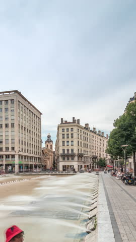 Hyperlapse of Place de la Republique in the historical center of Lyon, France. The square is dominated by a large fountain, surrounded by historic buildings, with people sitting on benches timelapse