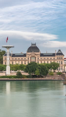 Panoramic hyperlapse view of the Rhone River and its embankment, featuring the University Jean-Moulin in Lyon, France. Includes the University Bridge and waterfront under a partly cloudy sky timelapse