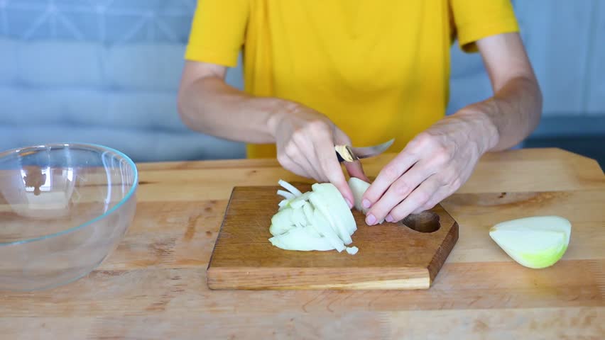 Woman slicing fresh onions a wooden cutting board, skillfully preparing ingredients a delicious homemade meal in kitchen video fullhd