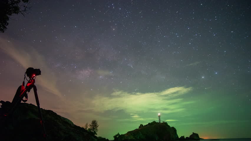 time lapse milky way above Lanta lighthouse.
The island where the lighthouse is located in the night. 
Lanta lighthouse is popular landmark of Krabi.
moving clouds obscuring the sky background.
