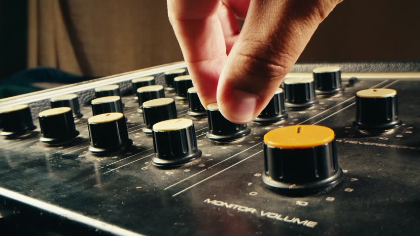 Music studio close up, Close up hands shot of sound engineer using mixing console, remote control for adjusting sound, audio mixer. Musician creates music, makes remix for DJ set. Sound recording