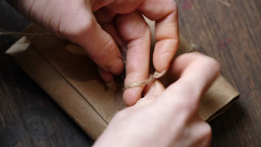 Top-Down Tying Knot on Leather Wallet Wrapped in Kraft Paper with Jute Twine
