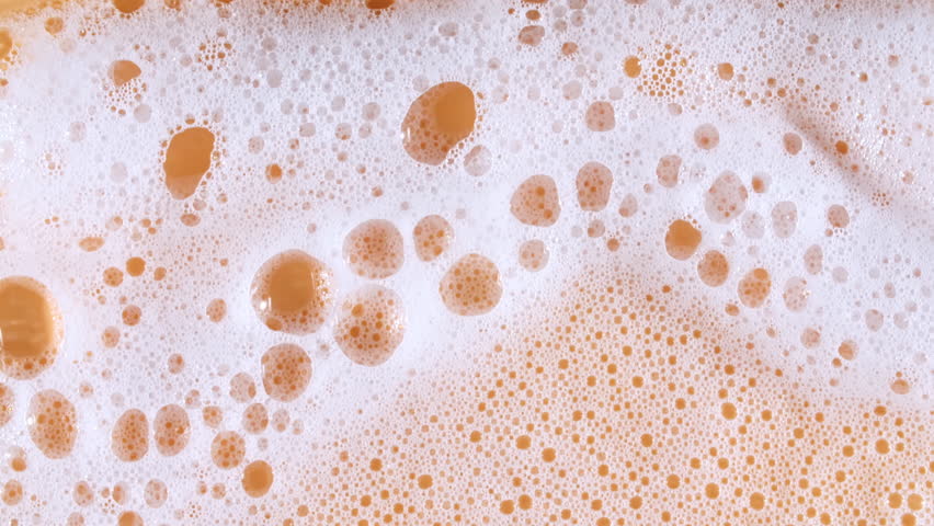 Bubbles of white soap foam. Moving Soap foam popping bubble on a orange backdrop. Soap sud macro structure. Clean, cleaning concept, laundry, shower. 