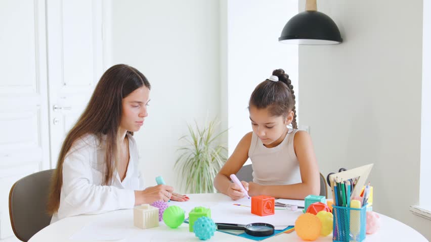 Speech therapist engages with child using colorful toys and art supplies in a bright, modern therapy space during a focused session,drawing art