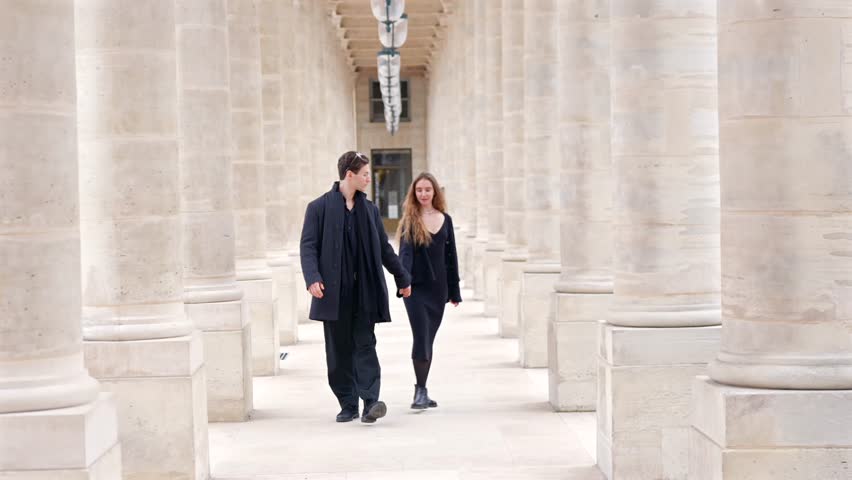 Couple walking through Palais Royal columns in Paris