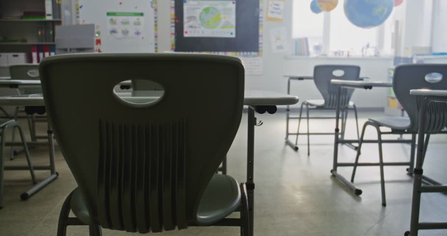 Interior of Modern Empty Primary School Classroom with Desks for Students, Chalkboard, Hanging Models of Solar System and Colorful Posters. Creative Space for Children Studying and Education Process.