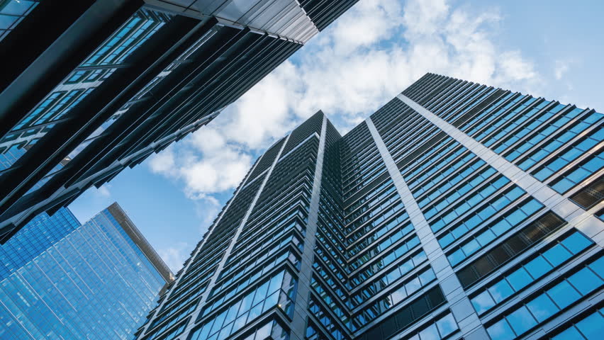 Wide angle hyperlapse shot of downtown high-rise glass skyscrapers on sunny day, financial district looking up tall modern architecture office buildings city center street, blue sky and white clouds