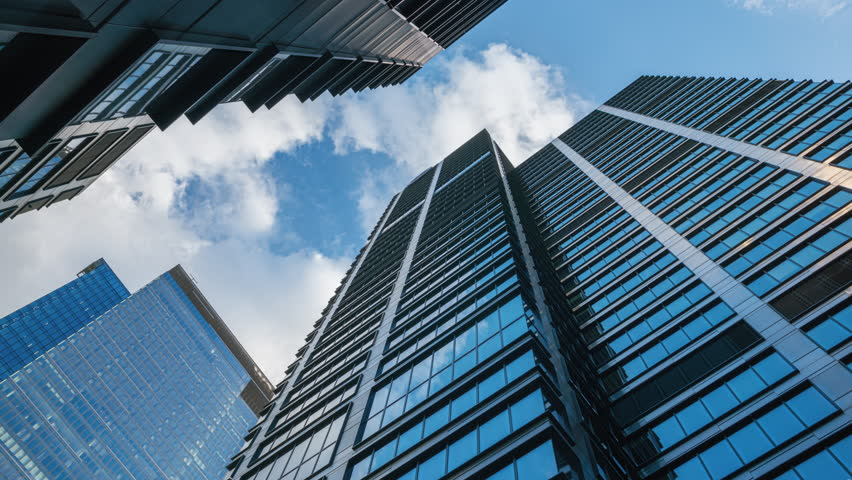 Wide angle hyperlapse shot of downtown high-rise glass skyscrapers on sunny day, financial district looking up tall modern architecture office buildings city center street, blue sky and white clouds