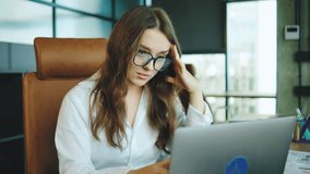 Young woman experiencing stress in a modern office environment while working on a laptop during a busy day filled with paperwork and deadlines - Powered by Shutterstock - Get 15% off with code: PIKWIZARD15